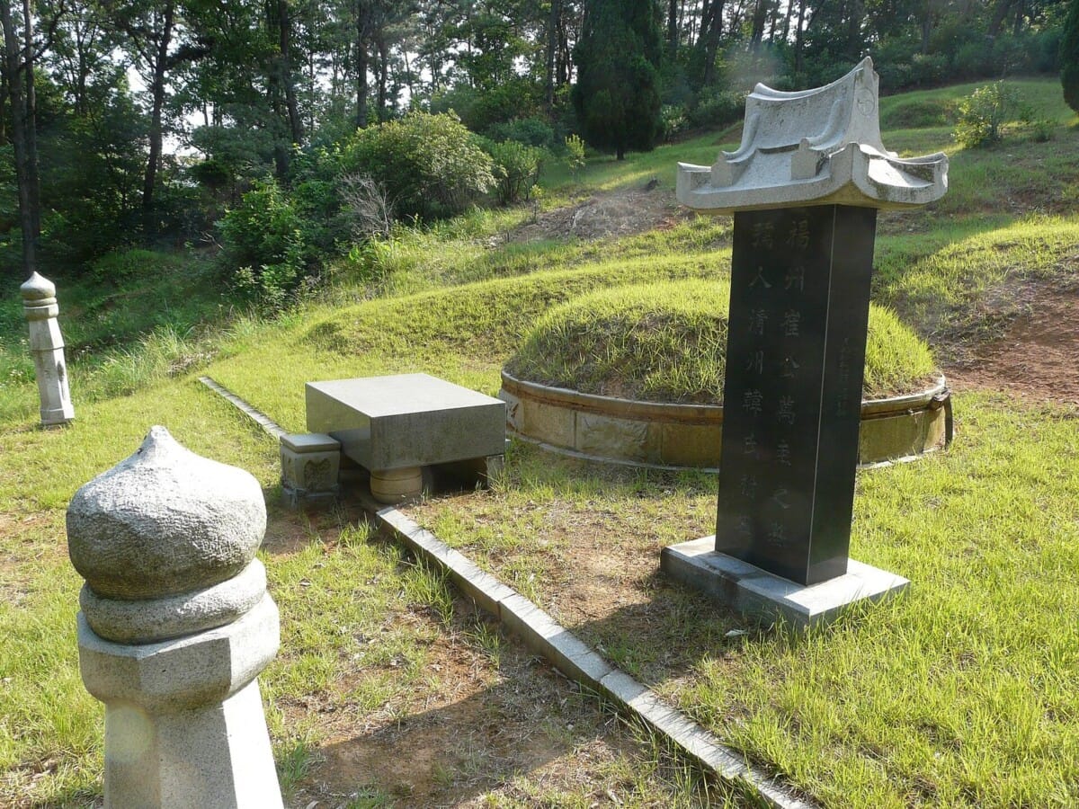 벌초를 앞둔 한국 전통 산소의 봉분과 비석, 주변 풀이 자란 모습